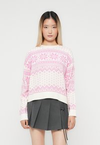 Young woman with straight ombre hair wearing a white and pink patterned sweater and a gray pleated skirt with side ties.