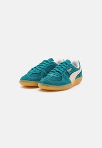 Tenis em camurça azul-turquesa com detalhes brancos e sola de borracha amarelo. Apresenta bico redondo, design com atacadores e detalhes cosidos na parte superior.