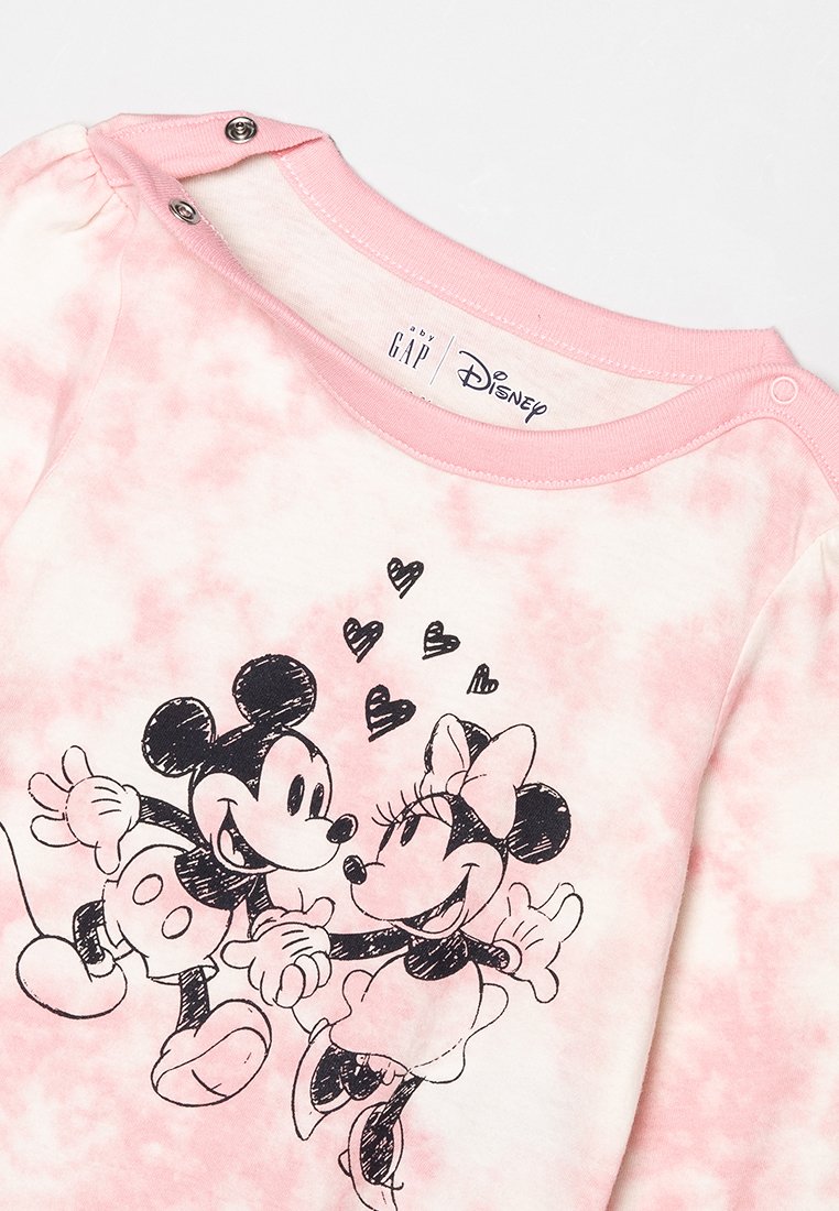 Camisa de manga larga de teñido en rosa, hecha de tela suave, con Mickey y Minnie Mouse en contorno negro, tomados de la mano con corazones encima.