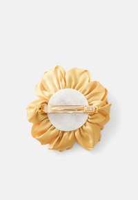 Fascetta per capelli con fiore di tessuto giallo, fondo in feltro bianco e fermaglio in metallo dorato, su sfondo bianco.
