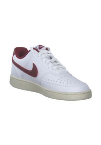Sneaker in pelle bianca con accenti color bordeaux, caratterizzata da dettagli perforati, una suola in gomma e lacci piatti. Logo Nike sul lato e sulla linguetta.