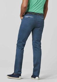 Pantalon en coton bleu pour homme, coupe slim, avec une ceinture à motifs, des poches arrière et une texture lisse, associé à des mocassins navy.