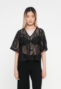 Svart cropped bluse med intrikate gjennomsiktige stoffmønstre og teksturerte detaljer, med V-hals og korte ermer.