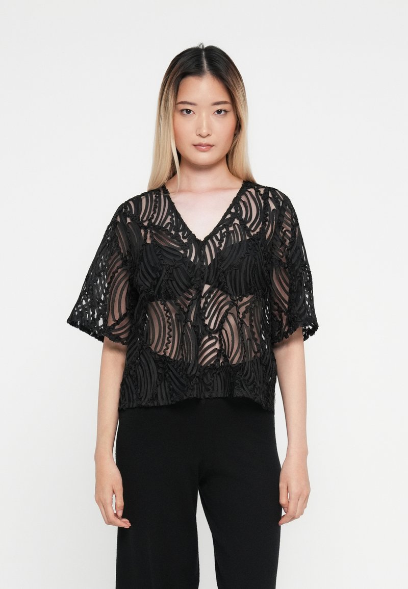 Svart cropped bluse med intrikate gjennomsiktige stoffmønstre og teksturerte detaljer, med V-hals og korte ermer.
