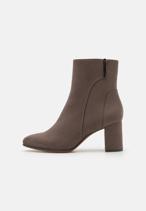 Bottines en suède marron avec un bout effilé, un talon en bloc et des détails de couture sur les côtés. Elles disposent d'une languette au dos pour un enfilage plus facile.