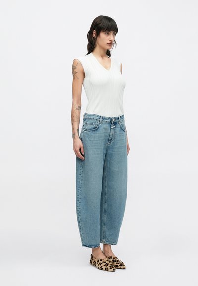 Λευκό ριγέ αμάνικο τοπ συνδυασμένο με ανοιχτό μπλε τζιν παντελόνι φαρδιάς γραμμής και φλατ παπούτσια με λεοπάρ μοτίβο, με άνετη εφαρμογή και βασικό στυλ.