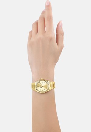 Goldfarbene Edelstahl-Uhr mit rundem Ziffernblatt, schlichtem Zifferblatt und Datumsanzeige, getragen an einer Hand mit neutralem Hautton.