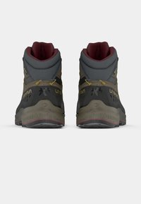 Augstu potītju pārgājienu apavi pelēkā un olīvzaļā krāsā ar sarkaniem akcentiem, aprīkoti ar teksturētu gumijas zoli un pastiprinātu potītes atbalstu.