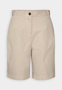 Shorts beige arrivant aux genoux, avec des passants de ceinture, des poches latérales et une fermeture à boutons à l'avant sur un fond blanc uni.
