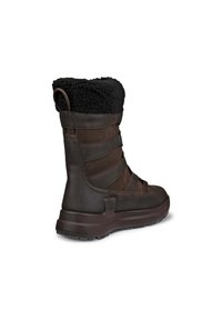 Botte imperméable marron foncé avec un revêtement en cuir texturé et un col en fausse fourrure noire. Équipée d'une semelle en caoutchouc moulé et de sangles réglables.