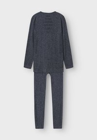 Tumedate sinine pikkade varrukatega pluus ja retuuside komplekt. Valmistatud tekstuurilisest kangast, millel on sile viimistlus. Omab ümarat kaelust ja istuvat lõiget.