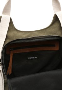 Canvas tote bag in olive green with cream straps, featuring a zippered pocket and brown leather accents, labeled with "MISAKO." Interior is black.