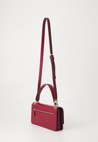 Borsa a tracolla rossa in pelle con tracolla staccabile, caratterizzata da una tasca frontale con zip e un design strutturato. Finiture in metallo dorato.