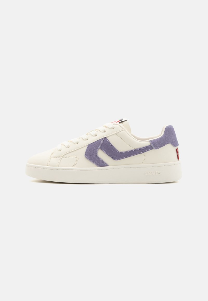 White sneaker featuring a soft purple suede accent, flat laces, a textured rubber sole, and a small red and white logo patch on the tongue.