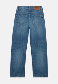 Vista trasera de unos vaqueros de pierna recta azules con dos bolsillos traseros y un parche del logo marrón de Tommy Hilfiger en la cinturilla.