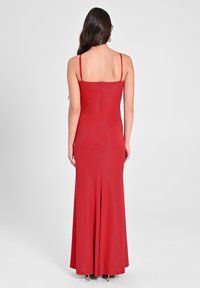 Rotes Kleid mit tailliertem Design, verstellbaren Spaghetti-Trägern, Rückenreißverschluss und ausgestellt geschnittenem unteren Saum, aus glattem Stoff gefertigt.