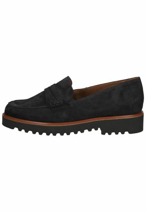 Mocassin en daim noir avec une bordure marron et une semelle crantée noire épaisse, doté d'une bride penny et d'un bout arrondi.