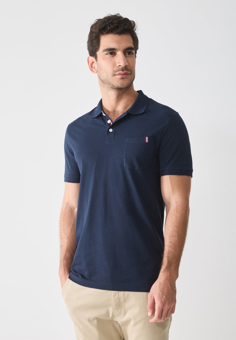Navyblauwe polo-shirt van katoen met een kraag, korte mouwen en een klein zakje met een accent van rood, wit en blauw gestreept.