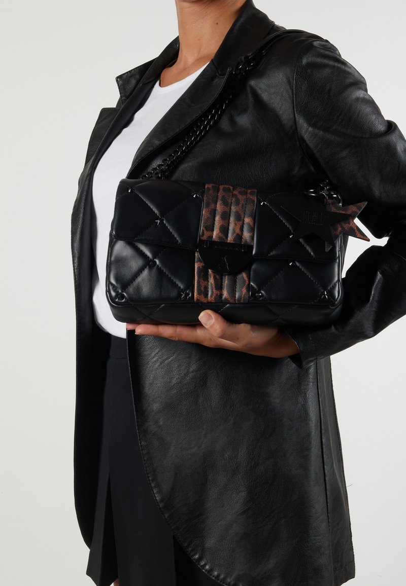 Kuitutettu musta nahkakäsilaukku, jossa on leopardikuosiset yksityiskohdat ja ketjuhihna. Laukussa on tähden muotoinen metallikoriste ja lukitus.