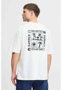 Hvid bomulds T-shirt med sort grafisk print på ryggen, der viser en sol, palmer og teksten "UNLIMITED SUMMER" i et rektangulært layout.