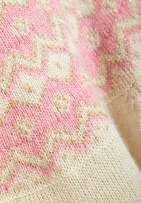 Knit fabric in cream with pink geometric patterns and subtle gold threads, featuring a soft texture and a cozy, layered design.