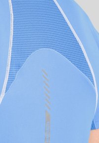 Blå atletisk skjorta med ett texturerat nätpanel, slätt tyg och reflekterande silverdetaljer. Erbjuder en strömlinjeformad, figursydd design.