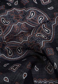 Tejido oscuro con un patrón que presenta diseños de paisley en blanco y naranja sobre un fondo texturizado en azul marino, con detalles intrincados en todo el diseño.