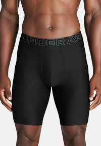 Schwarze, schmal geschnittene Boxershorts aus einem glatten Material, ausgestattet mit einem elastischen Bund mit Logo, entworfen für Komfort und Unterstützung.