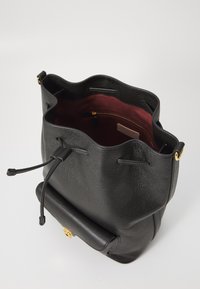 Borsa a secchiello in pelle nera con superficie texturizzata, bordo superiore scallopato e interno di un rosso profondo con una tasca con zip e hardware dorato.