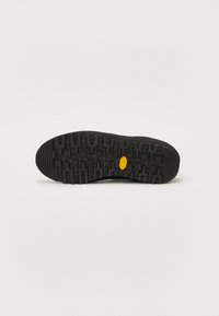 Talpa de pantof din cauciuc negru, cu un model de călcâi adânc și un logo accent galben. Suprafață texturată pentru aderență și durabilitate.