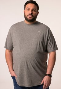 Šedé tričko s krátkým rukávem vyrobené z měkké tkaniny, s minimalistickým designem a nenápadným logem na hrudi, ve volném střihu.