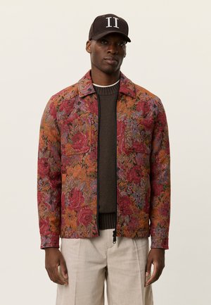 Veste à motif floral aux tons chauds de rouge, orange et bleu. Dotée d'une fermeture éclair à l'avant, de deux poches poitrine et d'un col.
