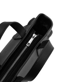 Mustast tekstuuriga nahast käekott kahe sangaga ja keskel h õbedane lukk poolenisti avatud, mida näha avar sisemus.