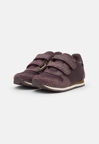 Sneaker bordeaux realizzati in tessuto testurizzato con due ampie cinture in Velcro e una suola bianca chiazzata. Punta arrotondata, colletto imbottito e dettaglio nero.