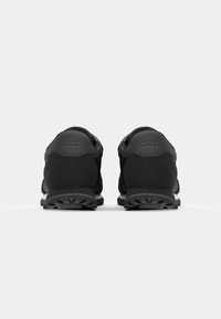 Zwarte sneakers met een slank ontwerp, gestructureerde stof, gewatteerde hiel, rubberen zool en subtiele branding die op de achterkant is gedrukt.