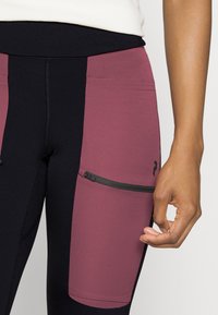 Svarta och vinröda träningsleggings med hög midja, sidoficka med dragkedja och kontrasterande färgpaneler för en snygg design.