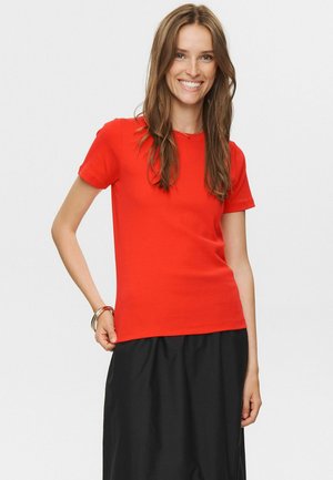 Red short-sleeve T-shirt in a smooth cotton blend with a fitted design. Paired with a black skirt, showcasing a simple neckline and clean lines.