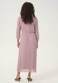 Lilac pleated midi dress with long sleeves, elastic waistband, and sheer fabric; back view shows textured pattern and flowy silhouette.