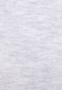 Jasnoszara, miękka faktura materiału z delikatnym wzorem dzianiny, ukazująca cienkie, równomiernie rozmieszczone nitki na całej powierzchni.