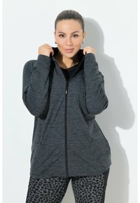 Felpa con zip di colore grigio scuro in un tessuto morbido e testurizzato, dotata di due tasche frontali e colletto alto, abbinata a leggings a stampa leopardata nera e grigia.