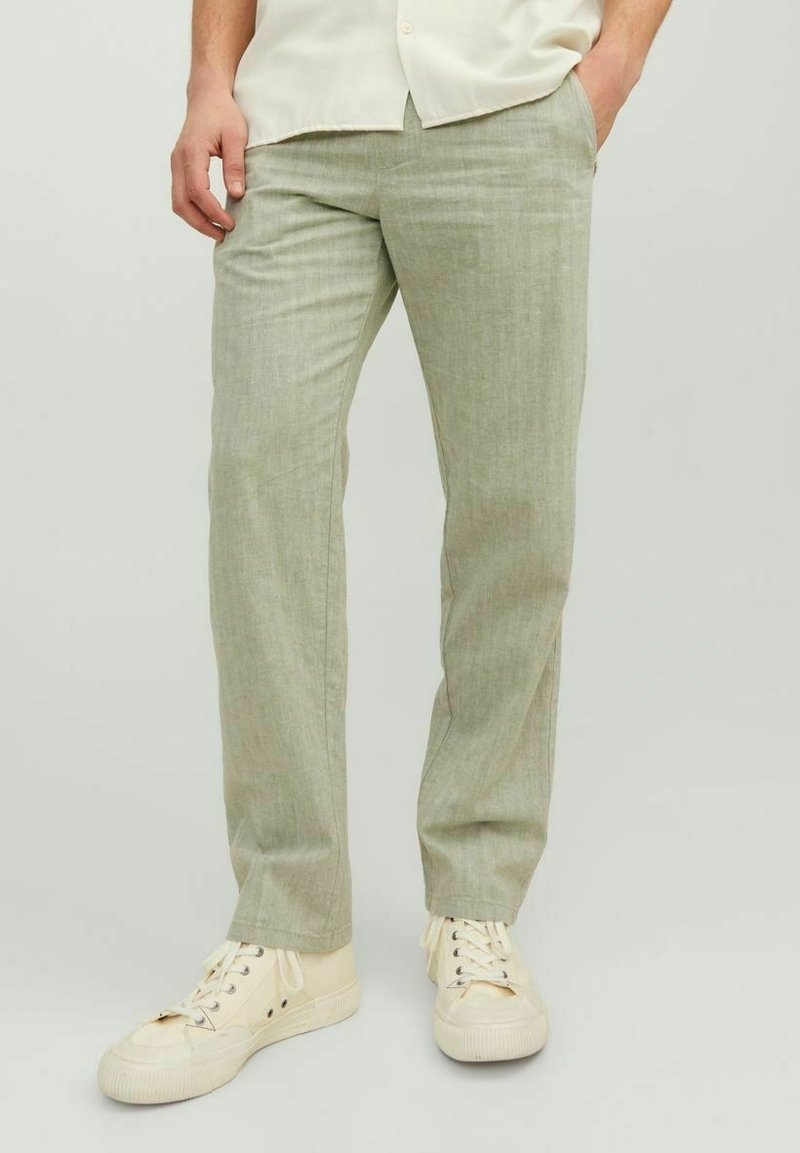 Ljust gröna linneblandade byxor med rak passform och subtil textur, tillsammans med off-white sneakers. Inga synliga mönster eller detaljer.