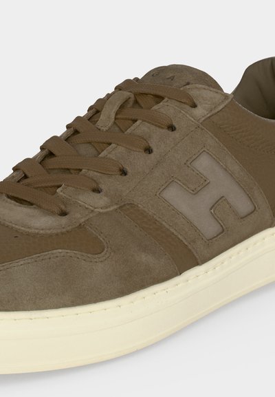 Baskets en daim et cuir marron avec lacets marron, un grand logo "H" sur le côté et une semelle en caoutchouc blanche.