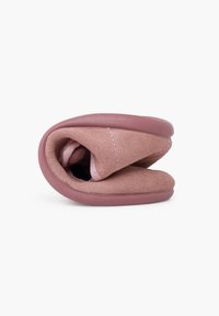 Zapatilla plegable de suave ante rosa con suela de goma. El interior presenta un forro de tela en un rosa más claro. Forma compacta y redondeada.