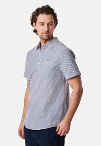 Camicetta a maniche corte con bottoni in un motivo a quadri blu navy e bianco, con colletto e tasca frontale. Materiale di cotone con una consistenza morbida.