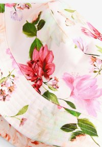 Ziedu cepure ar rozā auduma pamatu, uz kura attēloti daudzkrāsaini ziedi un zaļas lapas, ar smalku ribojumu un šūtām šuvēm.