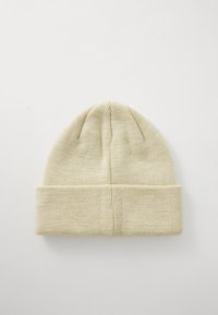 Strikket beanie i lys beige med en blød tekstur, der har en rullet kant og subtil ribbing ved kronen for pasform og varme.