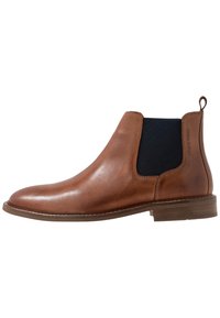 Botte Chelsea en cuir marron avec panneaux latéraux élastiques, bout arrondi et talon bas empilé. Finition lisse avec une languette à l'arrière.