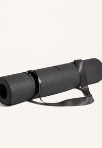 Svart yogamatta med mönster av texturerade vågor, rullad och fastsatt med en slank svart rem för enkel bärning.