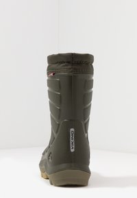 Bota impermeable verde con un acabado texturizado, diseño alto, suela de goma, cuello acolchado y un detalle de marca en el costado.