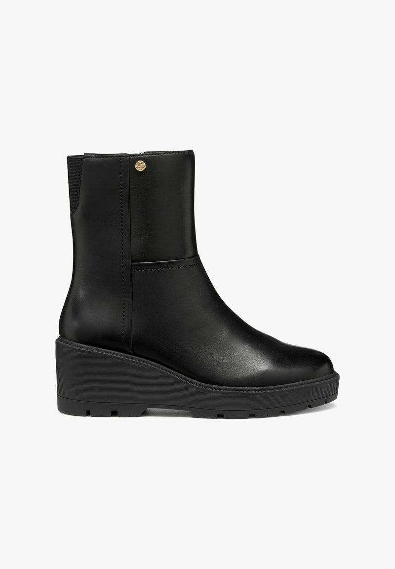 Bottine noire en cuir avec semelle compensée, bout arrondi, panneau latéral élastique et petit emblème doré près du bord supérieur.